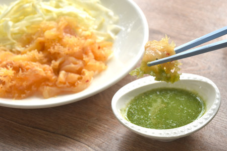 boiled jellyfish with slice cabbage on plate dipping Thai spicy and sour seafood sauceの写真素材