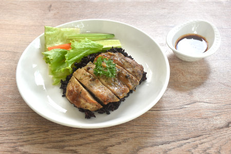 grilled slice chicken on black riceberry with cucumber carrot and lettuce on plate dipping Thai spicy tamarind sauceの写真素材