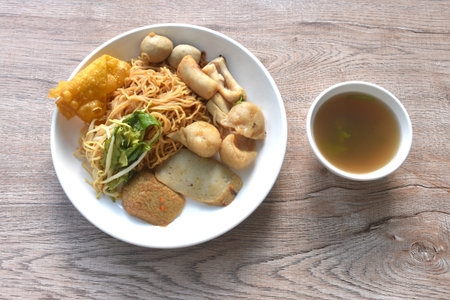 dry yellow egg noodles fishball with bean sprout topping crispy dumpling on plate with soup