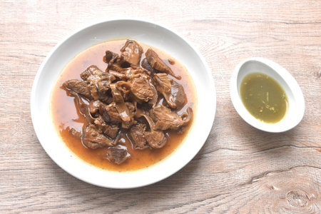 slice braised pork stew in herb brown soup dipping chili and sour sauce on plateの写真素材