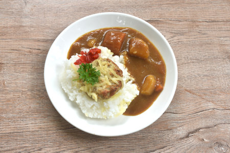 fried pork hamburg steak topping plain rice dressing potato and carrot in Japanese curry on plateの写真素材
