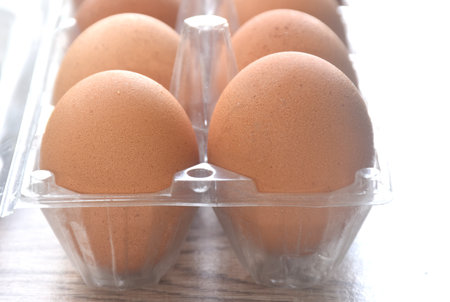 brown raw eggshell arranging in transparent plastic packing on wooden table
