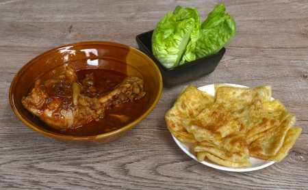 chicken leg massaman curry with slice crispy roti and baby cos lettuce on bowl
