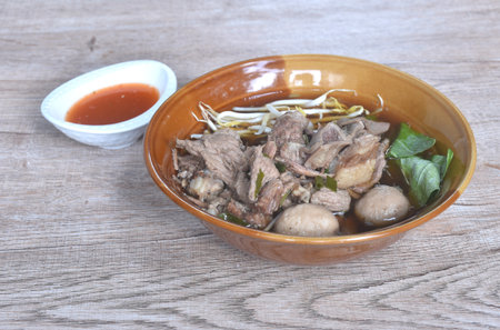 boiled braised pork meatball and tendon in herb brown soup on bowl dipping spicy chili sauce