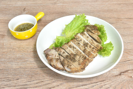 grilled slice salty pork loin with black pepper topping lettuce on plate dipping spicy hili sauce cupの写真素材