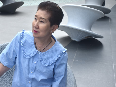 elder woman sitting and relaxing on chair in public park