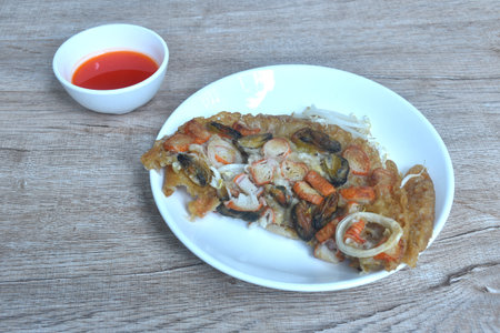 crispy fried egg and flour stuffed seafood with bean sprout on plate dipping chili sauceの写真素材