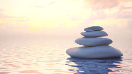 Zen stones stacked balance in the water at sunset.の写真素材