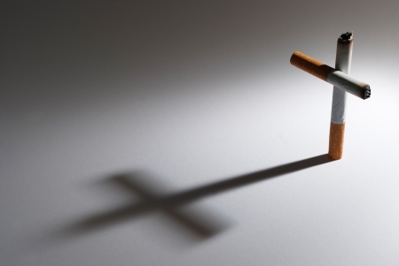 A cigarette with it shadow making a crossの写真素材