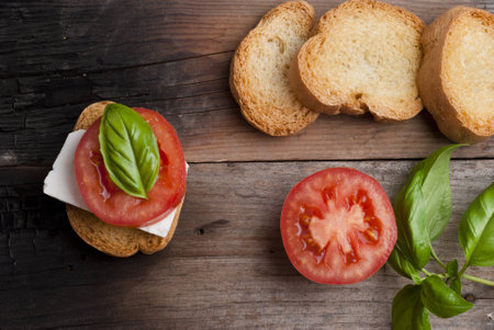 top-view of a wood table with an italian antipasto, with fresh cheese, tomato and basilの写真素材