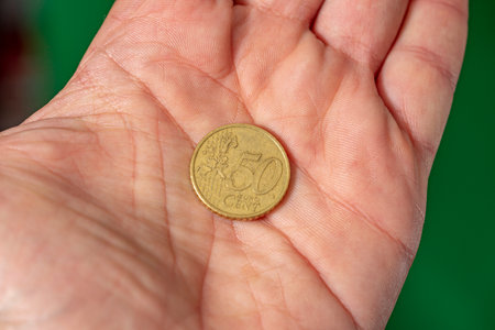 coin face of 50 euro cents on the palm. green backgroundの写真素材