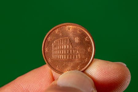 coin crown of 5 euro cents with the representation of the Coliseum in Rome held between the thumb...