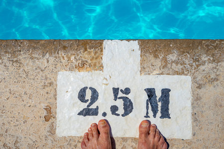 Female feet on the edge of a swimming pool with a sign