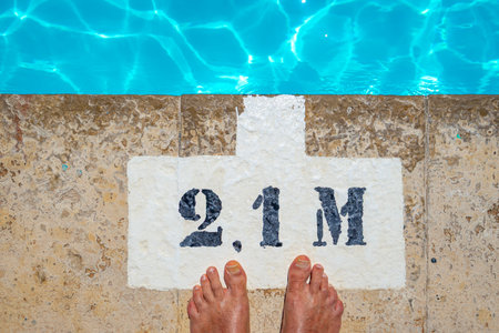 Man's feet on the edge of a swimming pool with a puzzle.の写真素材