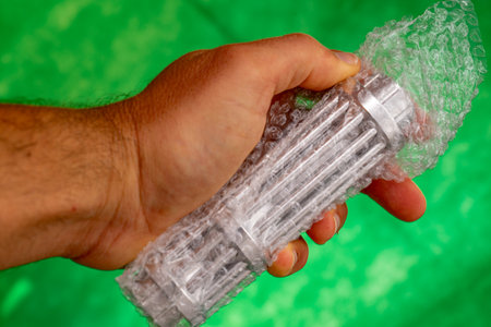 A man holds a plastic object in his hand on a green background