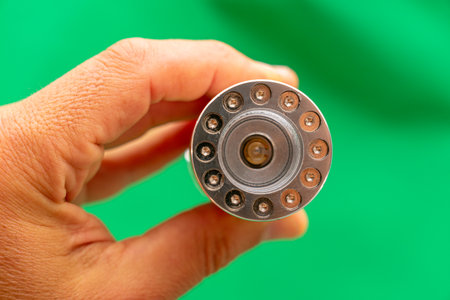Close up of a hand holding a new bearing on a green background