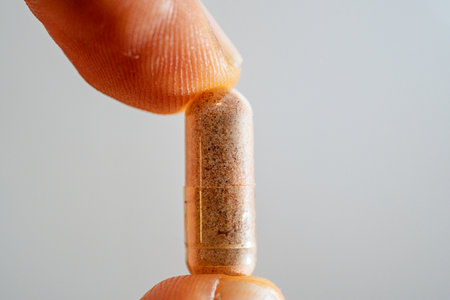 Close-up of a pill in a finger on a white background