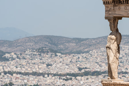 Detail of Caryatid of the Temple of Erechtheion, in the Acropolis of Athens, Greece. In the back ground, the city and the mountains of Athens.の写真素材