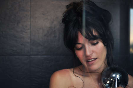 Portrait of young nude woman in slate stone shower with reflections on glassの写真素材