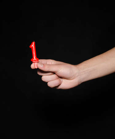 Hand holding up the number against a black background conceptual of numbers, measurement, amount, quantity, accounting, birthday and mathematicsの写真素材