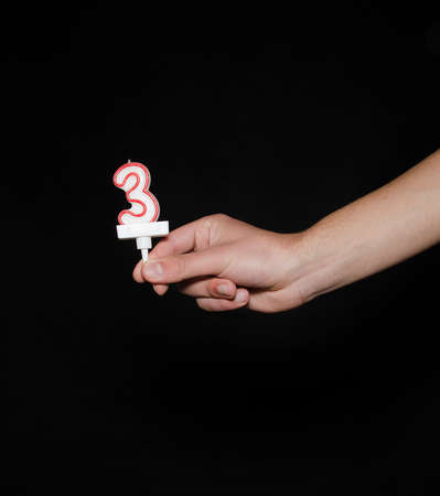 Hand holding up the number against a black background conceptual of numbers, measurement, amount, quantity, accounting, birthday and mathematicsの写真素材