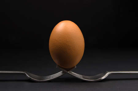 Brown egg holding on two forks, compositionの写真素材