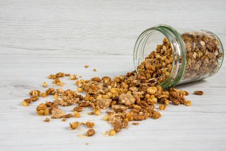 Jar full of granola  overturned on the white wood tableの写真素材