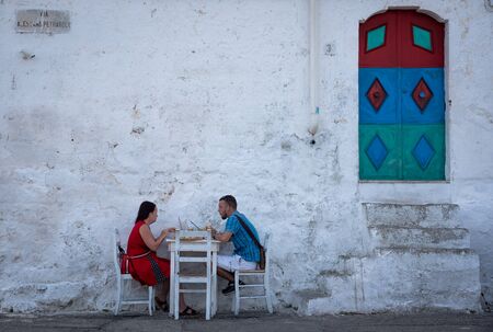 Ostuni, Italy - September 05 2019: A couple of tourists eating out of a restaurant in the historic center of Ostuni, Italy.のeditorial素材