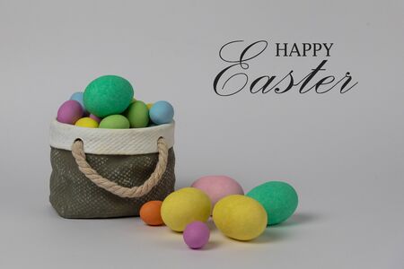 Colorful easter eggs with ceramic basket concept. Text Happy Easter on white background.