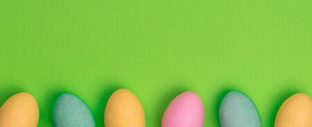 Easter colored eggs isolated on a green background. Copy space, minimal, top view.