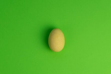 A yellow Easter egg isolated on a green background. Minimal, top view.の写真素材