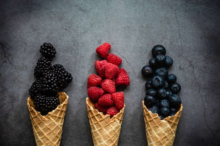 Fresh berries in waffle cones on dark stone background, top view. Concept healthy food and dessert.の写真素材