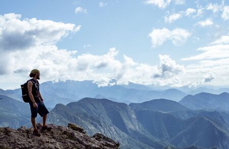 boy alone on a mountain looking at the horizon with beautiful views towards other mountainsの写真素材