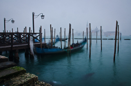 A Gondola gently moves with the movement of the water on Canal Grande with San Giorgio Maggiore in the background - a classical image of Venice, Italyの写真素材