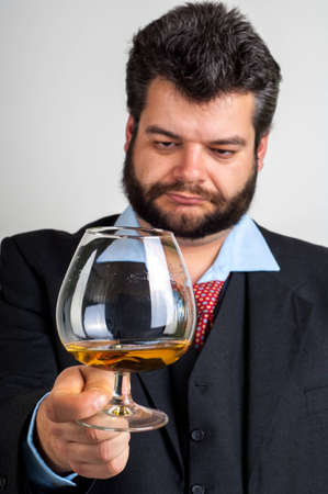 Businessman looking at a glass of whiskyの写真素材