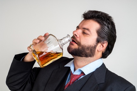 Drunk Businessman Drinking from a Bottle of whiskyの写真素材