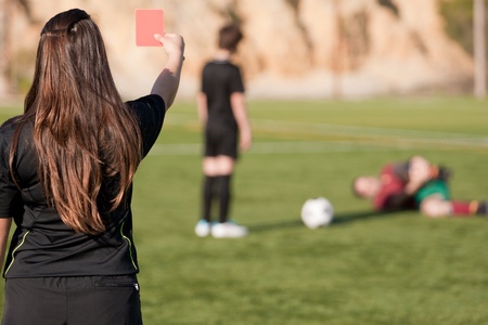 female referee showing the red card to the player with a injured player on the field