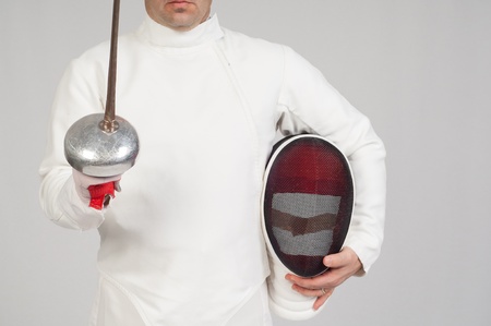 fencer athlete with sword and mask over grey backgroundの写真素材