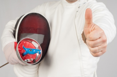 fencer athlete with sword and mask making ok sign over grey backgroundの写真素材