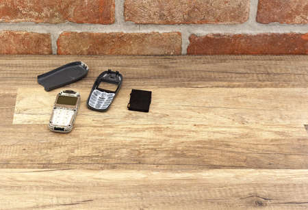 broken phone on the wooden floor at brick wall