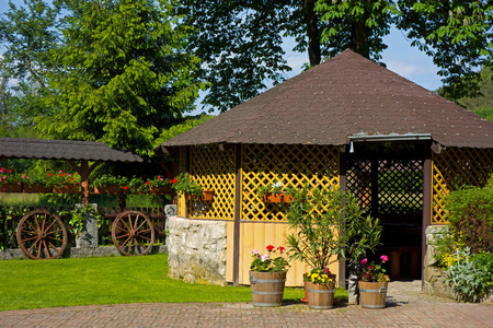 garden house, a fence decorated with flowers and two wheels of carriagesの写真素材