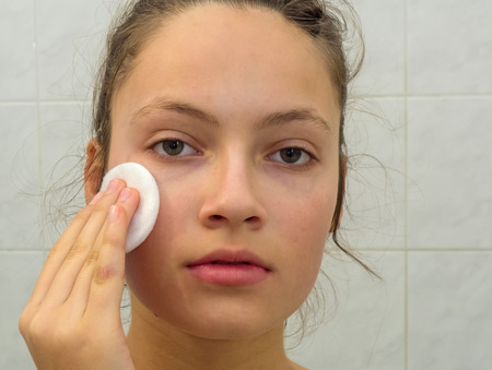 Young girl cleaning her skin with cosmetic padsの写真素材