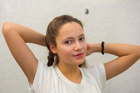 The girl in the bathroom adjusts her hair.の写真素材