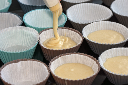 making muffins, filling the cups with batter