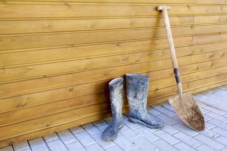 Shovel and gumboots based on a wooden wallの写真素材