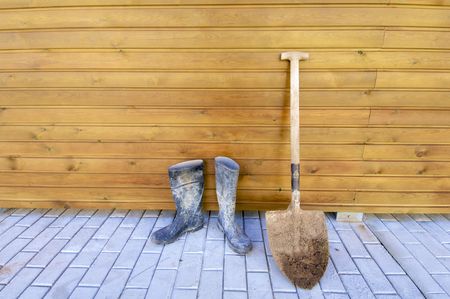 Shovel and gumboots based on a wooden wallの写真素材