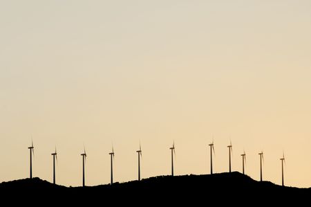 alignment of windmills on a hill with pink skyの写真素材