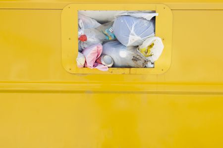 Detail of a yellow recycling container overflowingの写真素材