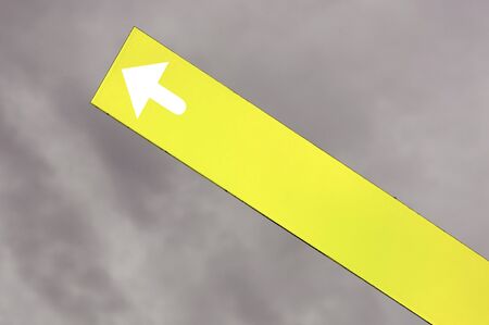 yellow arrow signal against a stormy skyの写真素材