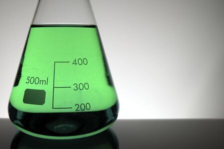 detail of a beaker with green liquid and white backgroundの写真素材